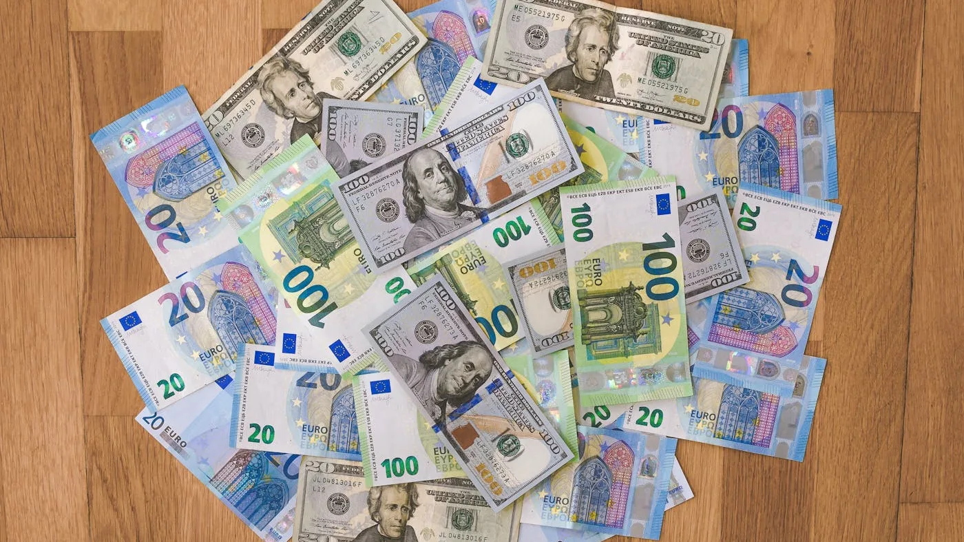 Cash dollars and euros stacked on a desk